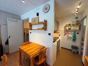 A compact kitchen with a wooden table, a microwave, and a sink. - Appartement 8 pers - 3 chambres - Résidence le Christiana - Centre village (Risoul 1850)