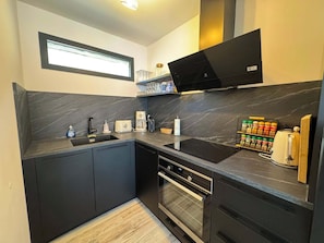 A modern kitchen with dark cabinetry, a built-in oven, a microwave, and a coffee maker. - Chalet Élégance - 8 pers - 3 chambres - 2 salles de bains (Risoul 1850)