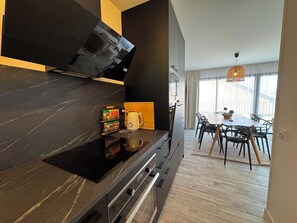Eine moderne Küche mit schwarzem Arbeitsplatz, einer Kaffeemaschine und einem Essbereich mit Tisch und Stühlen.