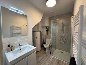 Moderni kylpyhuone, jossa on lasinen suihkuseinä, valkoinen pesuallas ja wc-istuin.
