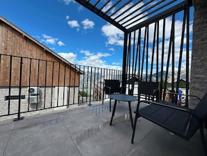 Ein Balkon mit Bergblick, ein Holzgebäude und eine Steinmauer.