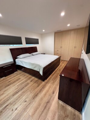 Une chambre à coucher avec un lit, un plancher en bois, une armoire et un bureau.