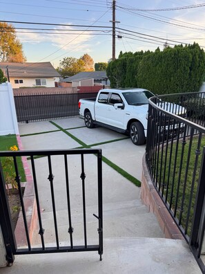 A gated driveway leading to a white pickup truck parked in a residential area with a clear sky. - Awesome 4-bedroom house with AC in charming Los Angeles (Los Angeles)