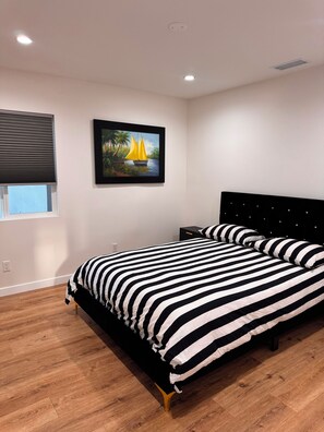 A bedroom with a bed, a nightstand, a framed painting, a window with blinds, and a ceiling light. - Awesome 4-bedroom house with AC in charming Los Angeles (Los Angeles)