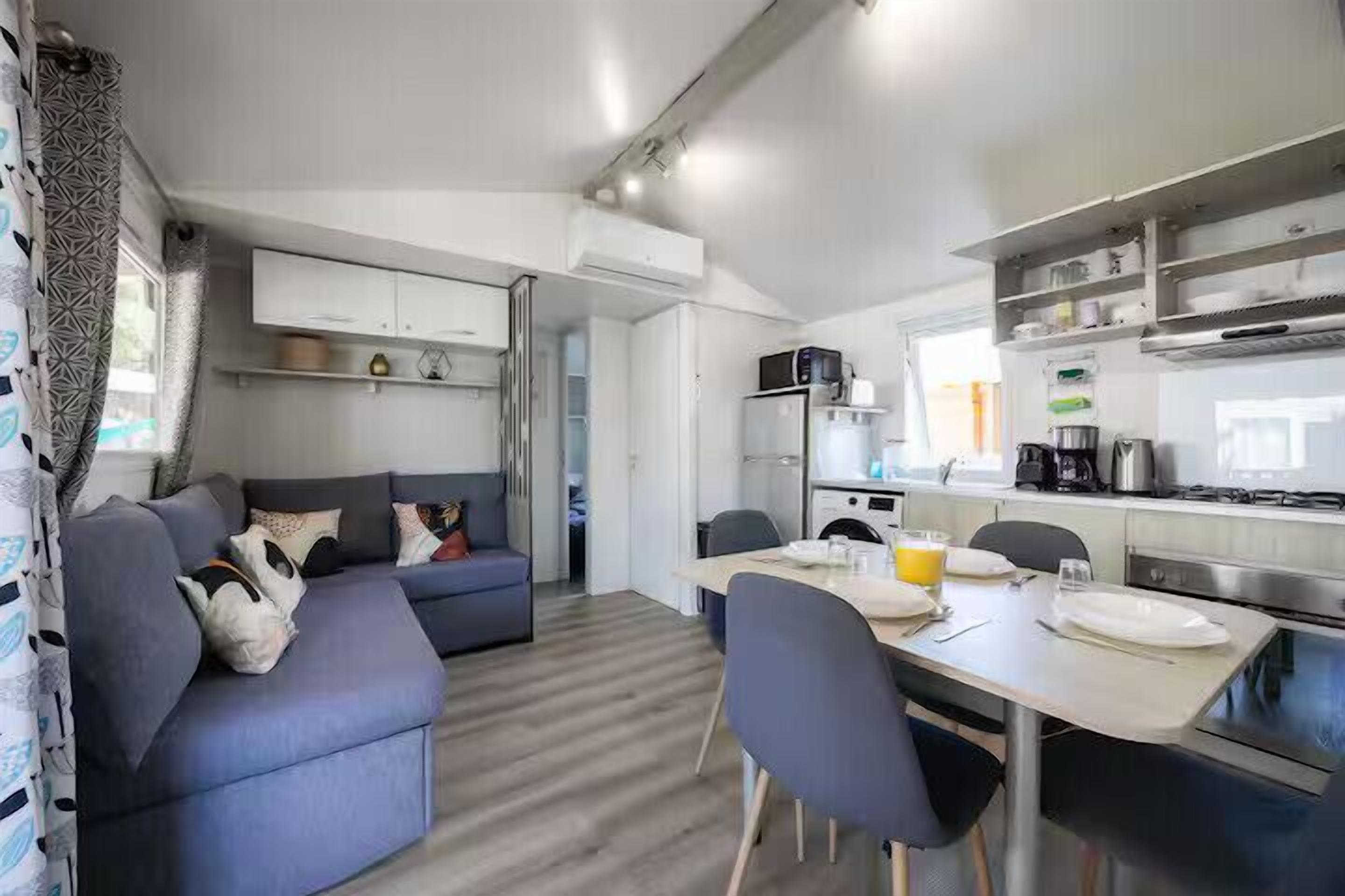 A compact living space with a sofa, dining table, and kitchenette.