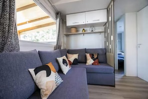 Ein modernes Wohnzimmer mit einer Eckcouch, einem Einbauschrank und Blick ins Freie.