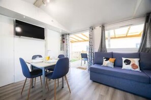 Ein modernes Wohnzimmer mit einer Couch, einem Esstisch mit Stühlen und einem an der Wand befestigten Fernseher.