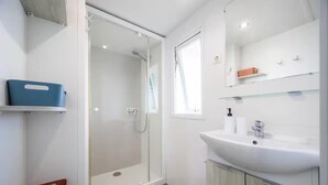 Un bagno moderno con box doccia in vetro, lavandino bianco e specchio sopra.