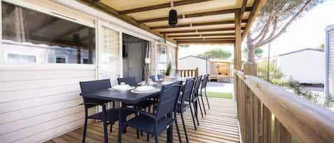 Un patio exterior con terraza de madera, una mesa lista para comer y vistas del entorno.