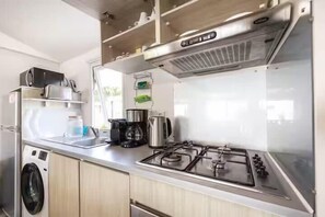 A compact kitchenette with a gas stove, a coffee maker, and a built-in oven.