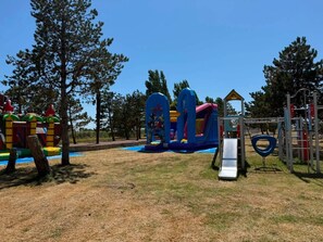 A playground with various play structures including a slide, climbing frames, and a small house. - Mobilhome 2 chambres 6 personnes (Saint-Thomas-de-Conac)