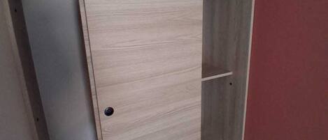 A wooden wardrobe with multiple shelves and a door.