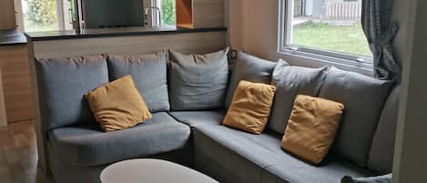 A modern living room with a grey sofa, a white coffee table, and a view of the outdoors.