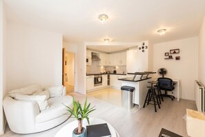 Eine moderne Wohnung mit Wohnbereich, Küchenzeile und Essplatz.