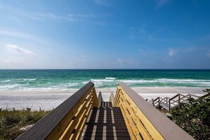 Ein Holzsteg führt zu einem Strand mit Blick auf den Ozean.