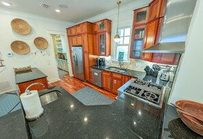 A modern kitchen with wooden cabinets, stainless steel appliances, and a black granite countertop. - Luxury Old Seagrove Retreat, Walk to Beach and Seaside, 3 King BRs, Private Heated Pool (Seagrove Beach)