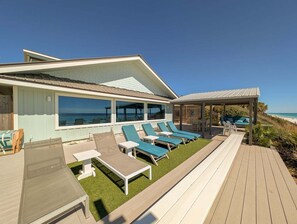 En ejendom ved kysten med en overdækket terrasse, udendørs møbler og havudsigt.