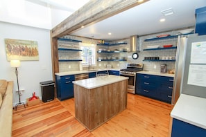 A modern kitchen with blue cabinets, a wooden island, and a stainless steel stove. - Luxury Old Seagrove Retreat, Walk to Beach / Seaside, Private Heated Pool, Game Room, Pet Friendly (Seagrove Beach)