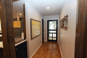 A hallway with wooden flooring, a framed picture on the wall, and a door leading to another room. - Luxury Old Seagrove Retreat, Walk to Beach / Seaside, Private Heated Pool, Game Room, Pet Friendly (Seagrove Beach)