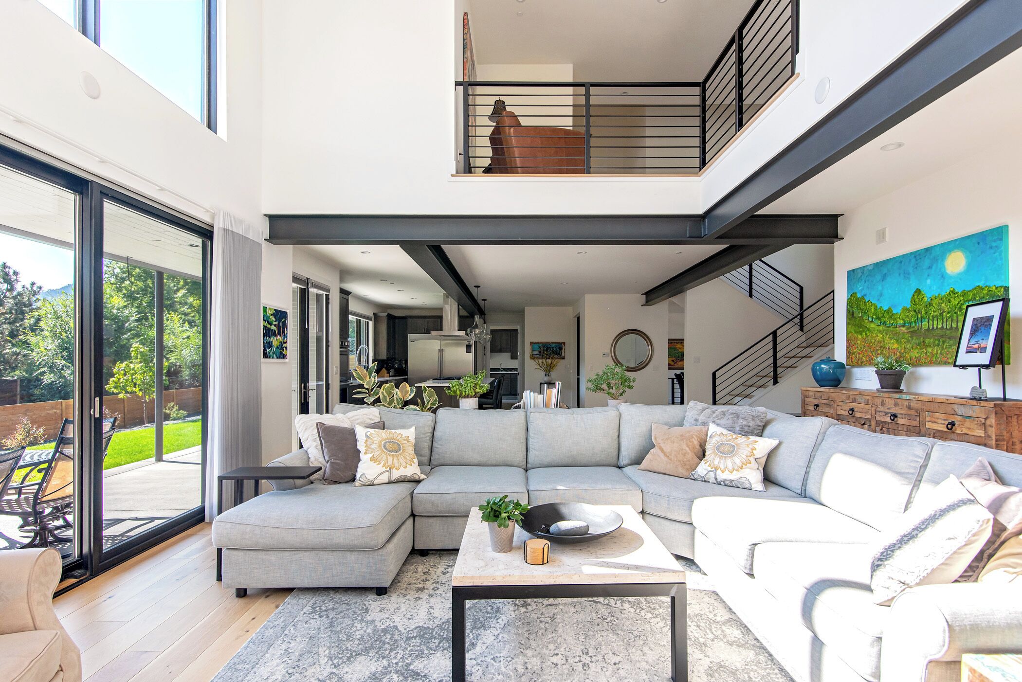 A modern living room with a sectional sofa, a coffee table, and a staircase leading to an upper level.
