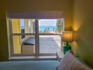 Habitació amb un gran finestral que dona a un terrat de fusta i l'oceà.