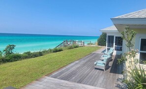 A wooden deck with outdoor furniture, a grassy lawn, and a view of the ocean. - Yellow House, Gulf Front, Private Steps to Beach (Seagrove Beach)