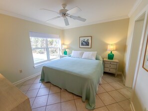 A bedroom with a bed, two bedside tables with lamps, a ceiling fan, a window, and a framed picture on the wall. - Yellow House, Gulf Front, Private Steps to Beach (Seagrove Beach)