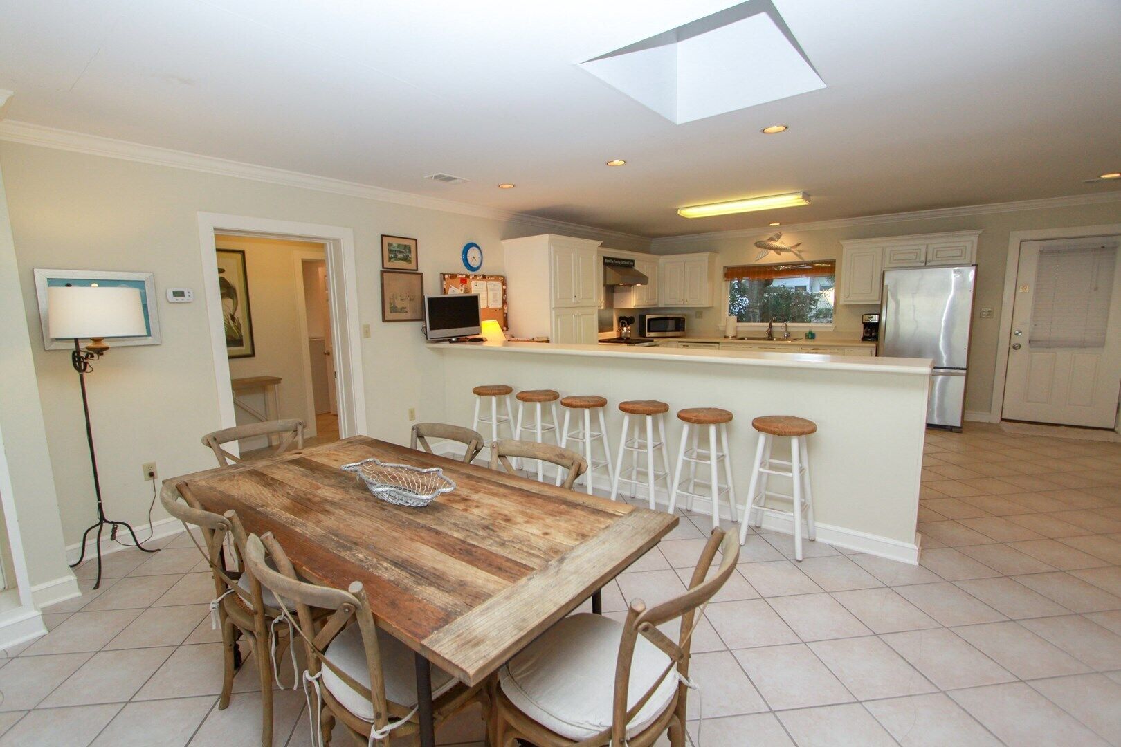 A modern kitchen with a central island, white cabinetry, and a dining area with a wooden table and chairs.