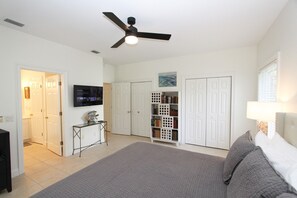 A bedroom with a bed, a ceiling fan, a TV, a bookshelf, and white wardrobes. - L'escapade, Old Seagrove, Near Seaside, Private Heated Pool, Close to Beach (Seagrove Beach)