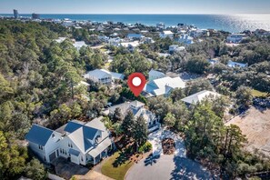 An aerial view of a residential area with houses surrounded by trees, a clear view of the ocean, and a red location marker. - L'escapade, Old Seagrove, Near Seaside, Private Heated Pool, Close to Beach (Seagrove Beach)
