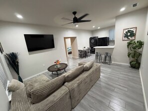 A modern living room with a sofa, a coffee table, and a TV mounted on the wall.
