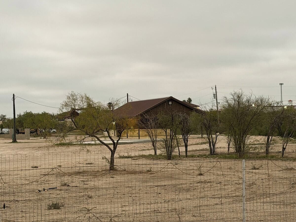 Uma área cercada com vegetação rasteira e um único edifício com telhado metálico.