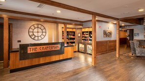 Un área de recepción con un mostrador de madera, un reloj y un cartel en la pared que dice 'THE CRAFTSMAN'.