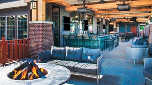 An outdoor patio with a fire pit, seating area, and bar.