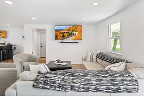 Una sala de estar moderna con un sofá, una mesa de centro y un televisor montado en la pared.