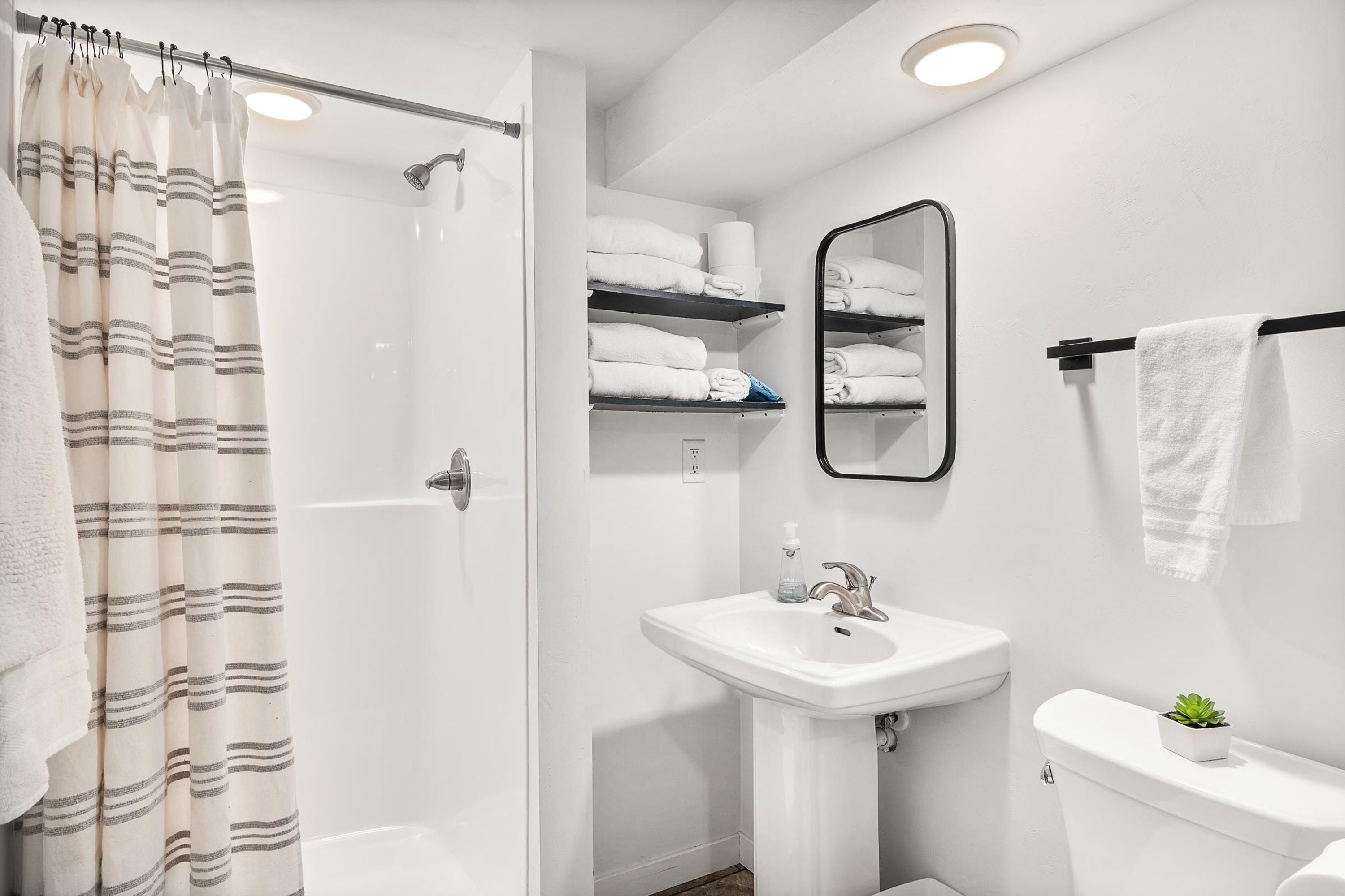 Ein Badezimmer mit Dusche, Waschbecken, Toilette und Spiegel.