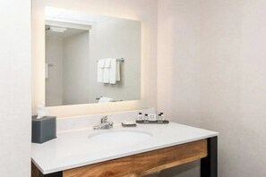 Een moderne badkamer met een wit wastafelmeubel, een spiegel en een handdoekrek.