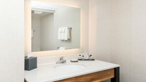 Ein modernes Badezimmer mit einem weißen Waschbecken, einem Spiegel und einem Handtuchhalter.