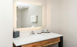 Een moderne badkamer met een wit wastafel, een spiegel en een handdoekhouder.