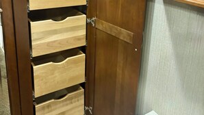 Une armoire en bois avec de nombreux tiroirs et une porte-miroir.