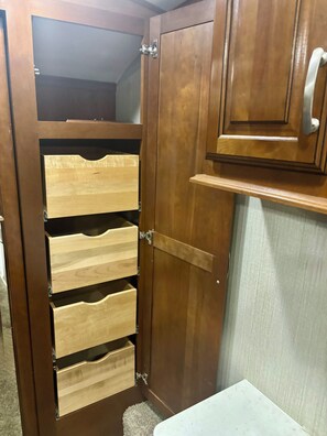 A wooden wardrobe with multiple drawers and a mirrored closet door.