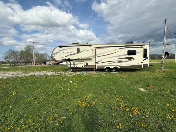 A recreational vehicle (RV) parked on a grassy field with a clear sky.