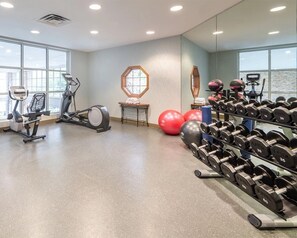 Un gimnasio con máquinas de cardio, equipo de levantamiento de pesas y pelotas de ejercicio.