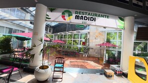 Un restaurante con terraza, entrada de cristal y plantas en macetas.
