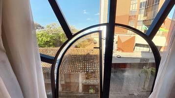 A view through a window with a metal frame, a tiled roof, and a building with a sign that reads 'BNB'.
