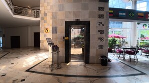 A lobby with a marble floor, an elevator, and a view of the outdoor seating area. - Gran Hotel Santa Cruz  (Santa Cruz)