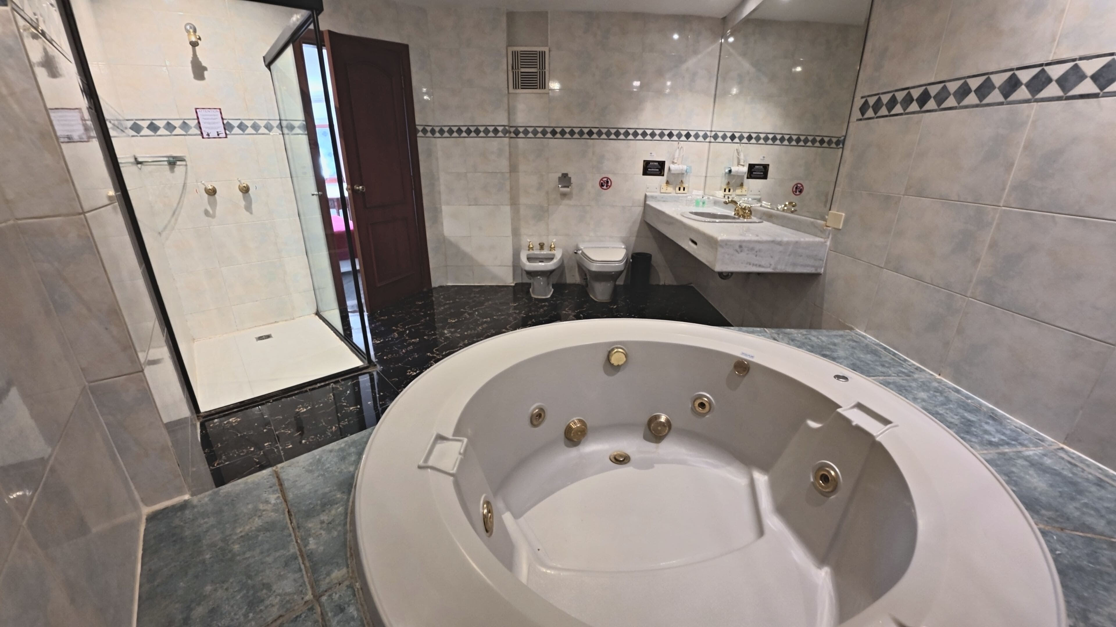 A modern bathroom with a large bathtub, a shower area, a toilet, and a sink.