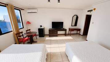 Une chambre d’hôtel avec deux lits, un bureau, une chaise, une télévision et une fenêtre avec des rideaux.