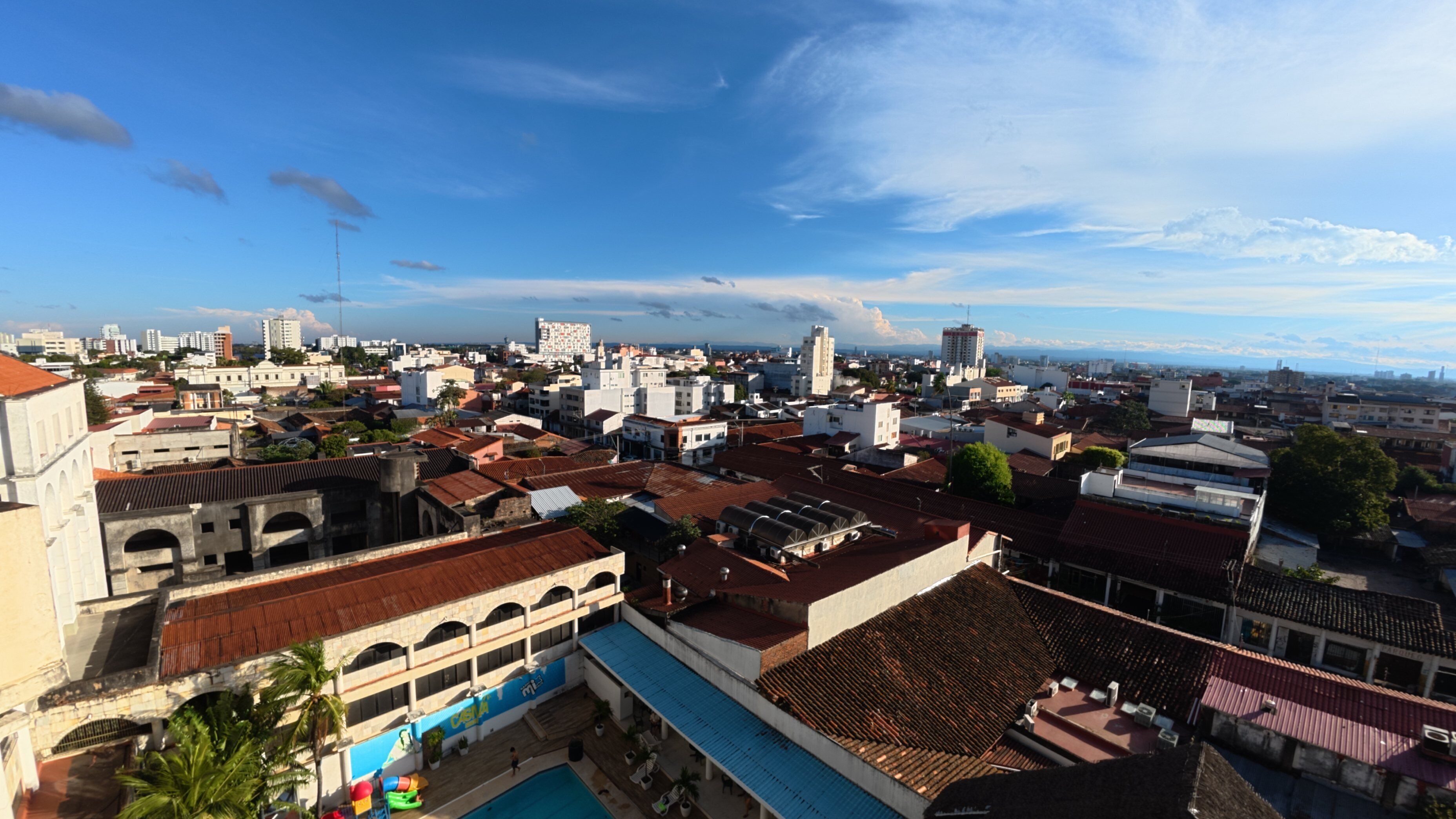 A cityscape with a variety of building styles, including some with red-tiled roofs and others with flat designs.