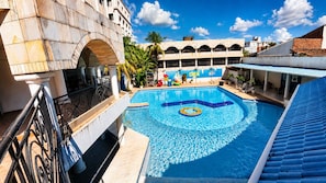 Una piscina con un centro decorativo, rodeada por un edificio con techo azul y un mural.